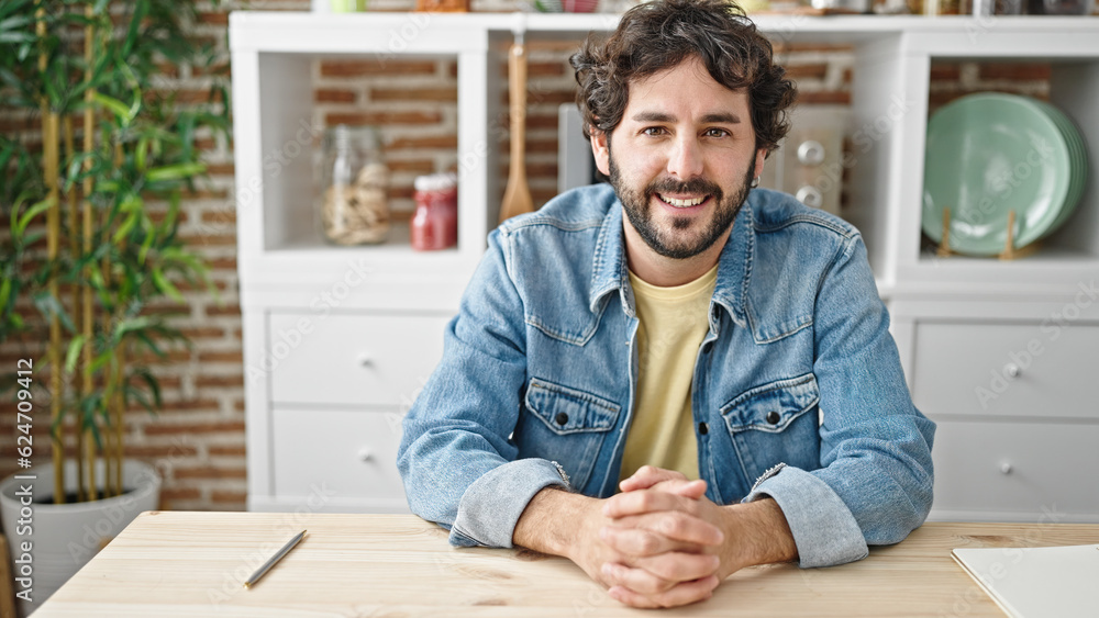 Young hispanic man smiling confident sitting on table at dinning room Young hispanic man smiling confident sitting on table at dinning room