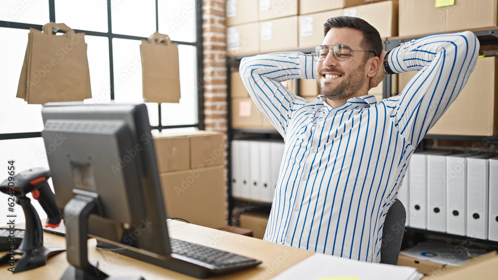 Young hispanic man ecommerce business worker working relaxed with hands on head at office