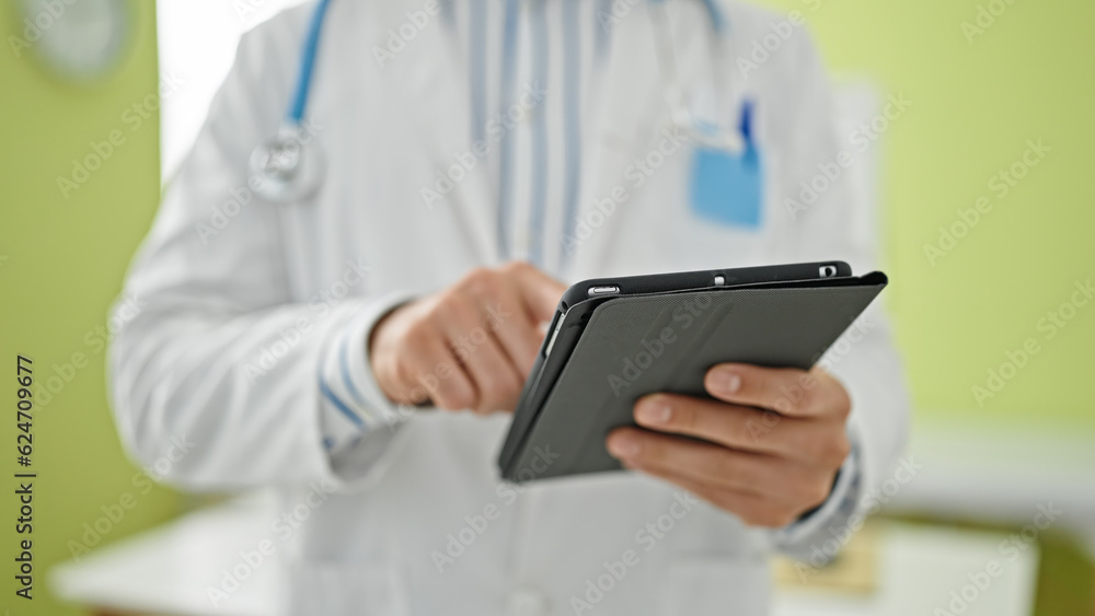 Young hispanic man doctor using touchpad at clinic Young hispanic man doctor using touchpad at clinic