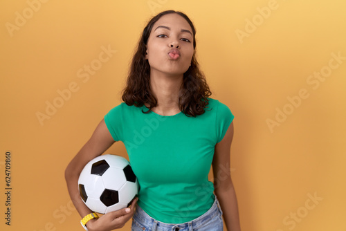 Young hispanic woman holding ball looking at the camera blowing a kiss on air being lovely and sexy. love expression. © Krakenimages.com