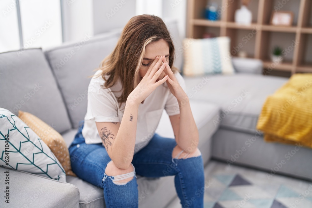 Young woman stressed sitting on sofa at home Young woman stressed sitting on sofa at home