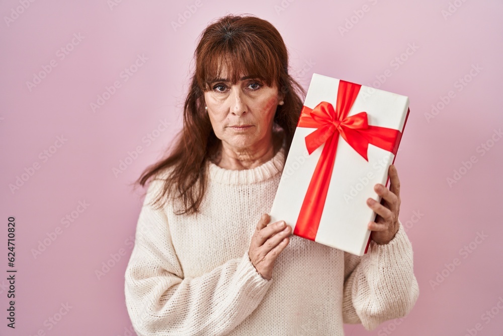 Middle age hispanic woman holding present depressed and worry for distress, crying angry and afraid. sad expression. Middle age hispanic woman holding present depressed and worry for distress, crying angry and afraid. sad expression.