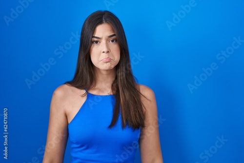Hispanic woman standing over blue background depressed and worry for distress, crying angry and afraid. sad expression.