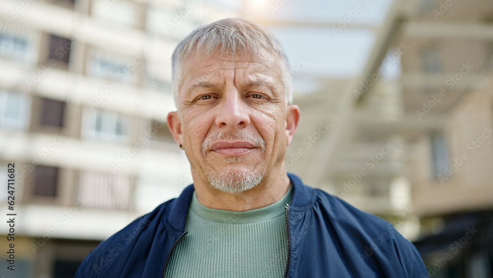 Middle age grey-haired man standing with serious expression at street Middle age grey-haired man standing with serious expression at street