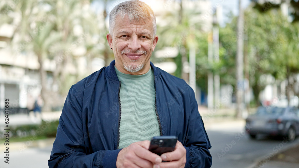 Middle age grey-haired man smiling confident using smartphone at park Middle age grey-haired man smiling confident using smartphone at park