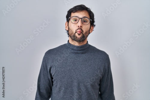 Handsome latin man standing over isolated background making fish face with lips, crazy and comical gesture. funny expression. © Krakenimages.com