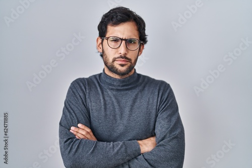 Handsome latin man standing over isolated background skeptic and nervous, disapproving expression on face with crossed arms. negative person. © Krakenimages.com