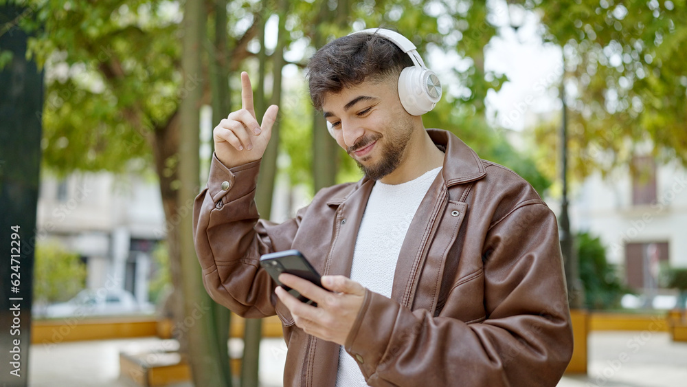Fototapeta premium Young arab man smiling confident listening to music and dancing at park