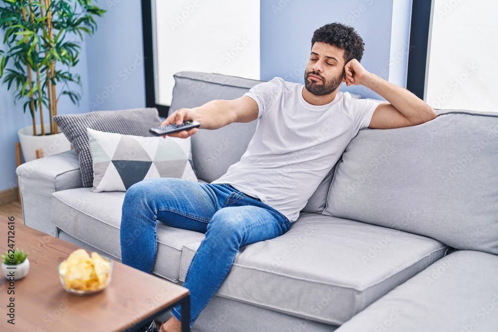 Young arab man watching movie sitting on sofa at home Young arab man watching movie sitting on sofa at home