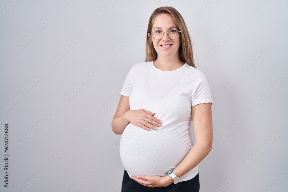 Young pregnant woman expecting a baby, touching pregnant belly smiling with a happy and cool smile on face. showing teeth. Young pregnant woman expecting a baby, touching pregnant belly smiling with a happy and cool smile on face. showing teeth.
