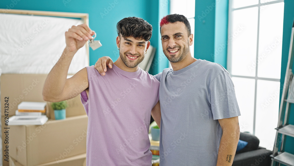 Obraz premium Two men couple hugging each other holding keys at new home