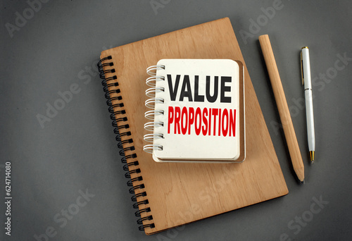 VALUE PROPOSITION text on notebook with pen and pencil on grey background