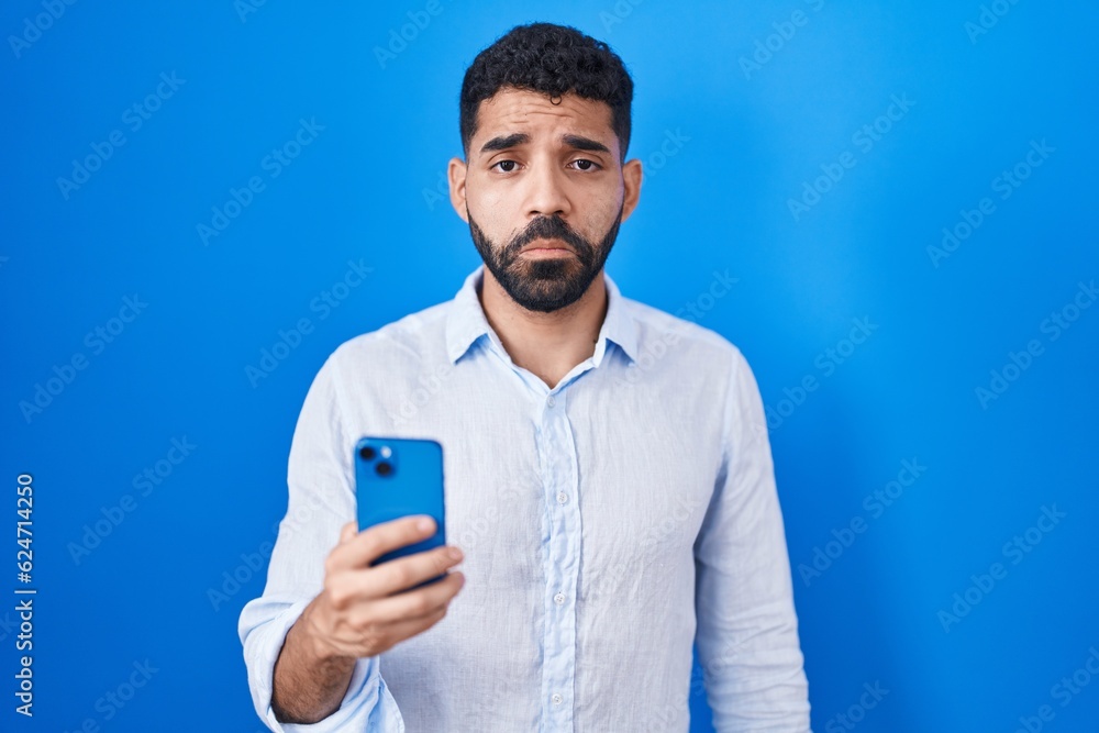 Hispanic man with beard using smartphone typing message depressed and worry for distress, crying angry and afraid. sad expression. Hispanic man with beard using smartphone typing message depressed and worry for distress, crying angry and afraid. sad expression.