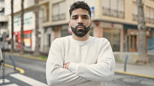 Young hispanic man standing with serious expression and arms crossed gesture at street © Krakenimages.com