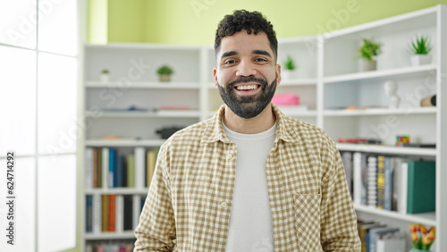 Young hispanic man student smiling confident standing at library university