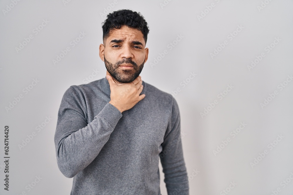 Hispanic man with beard standing over white background touching painful neck, sore throat for flu, clod and infection Hispanic man with beard standing over white background touching painful neck, sore throat for flu, clod and infection