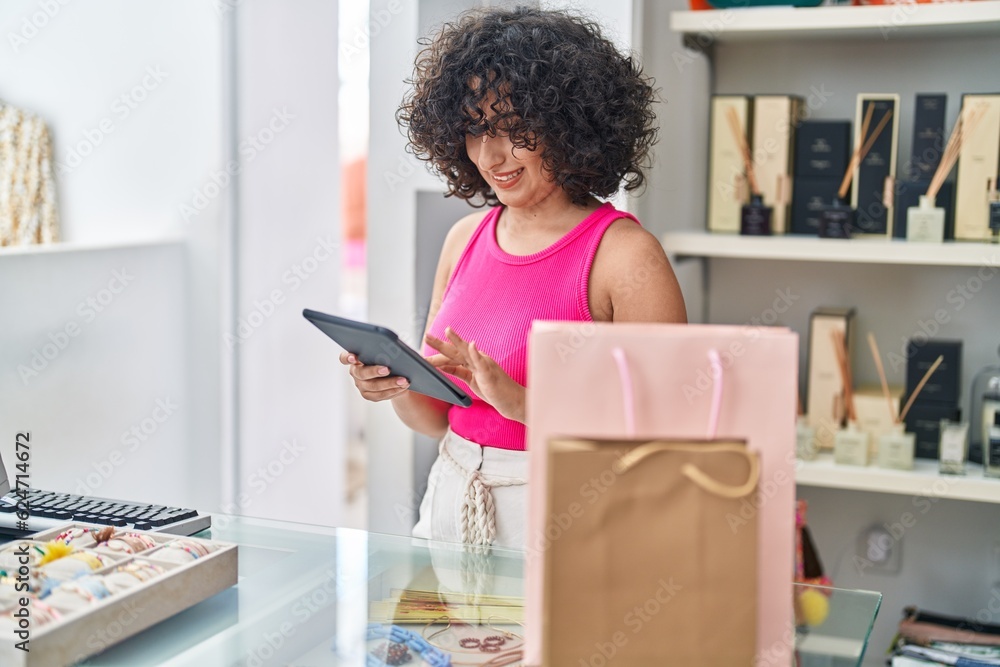 Young middle eastern woman shop assistant using touchpad working at clothing store Young middle eastern woman shop assistant using touchpad working at clothing store