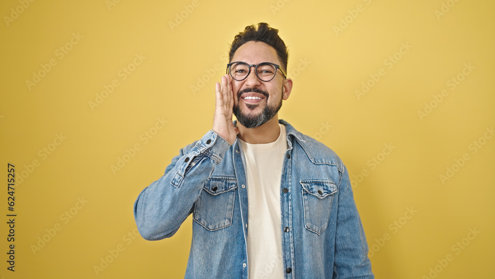 Obraz premium Young latin man smiling confident standing over isolated yellow background