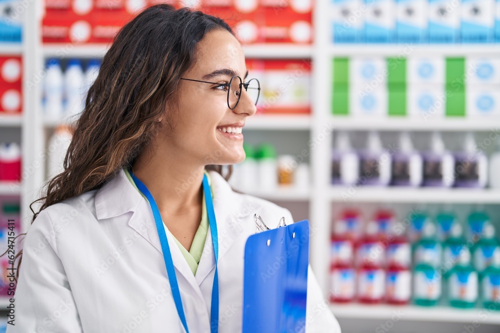 Young beautiful hispanic woman pharmacist smiling confident holding clipboard at pharmacy