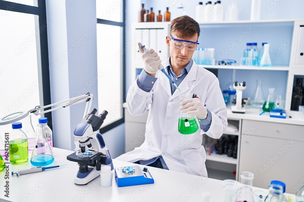 Young man scientist pouring liquid on test tube at laboratory Young man scientist pouring liquid on test tube at laboratory