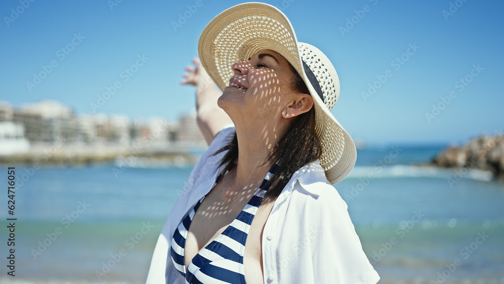 Middle age hispanic woman tourist standing with open arms at the beach