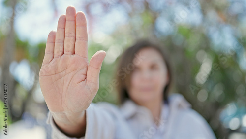 Middle age hispanic woman doing stop gesture with hand at park © Krakenimages.com