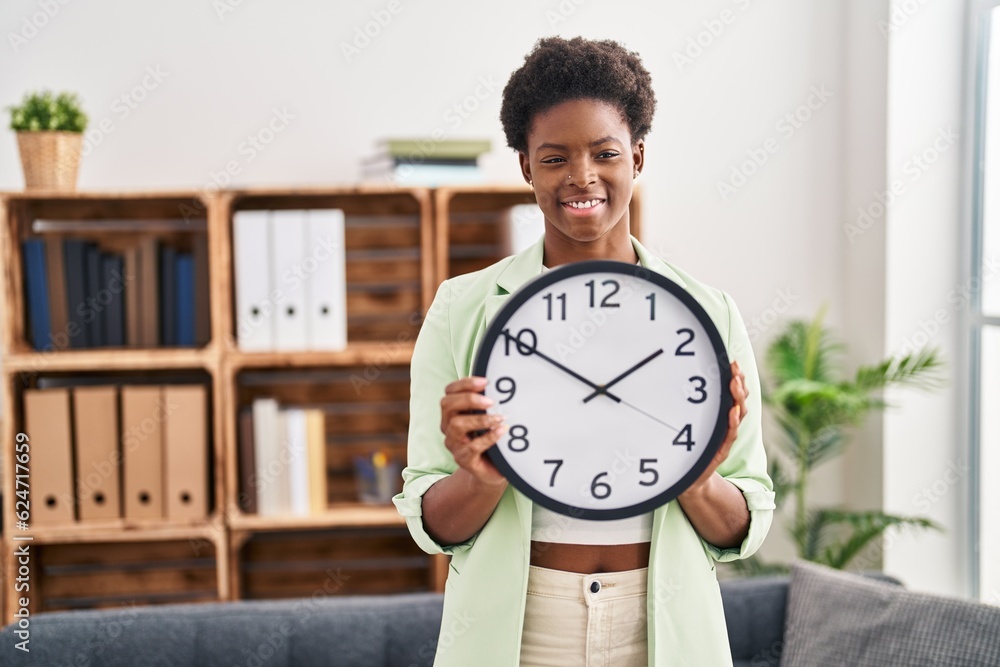 African american woman holding big clock smiling with a happy and cool smile on face. showing teeth. African american woman holding big clock smiling with a happy and cool smile on face. showing teeth.