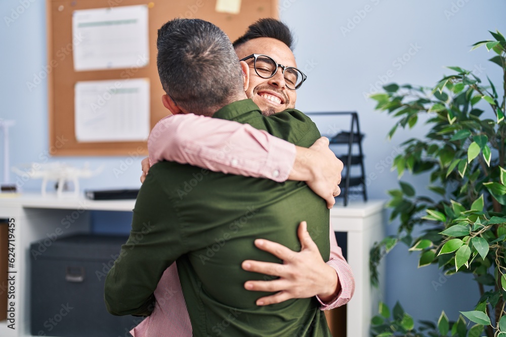 Fototapeta premium Two men business workers hugging each other at office