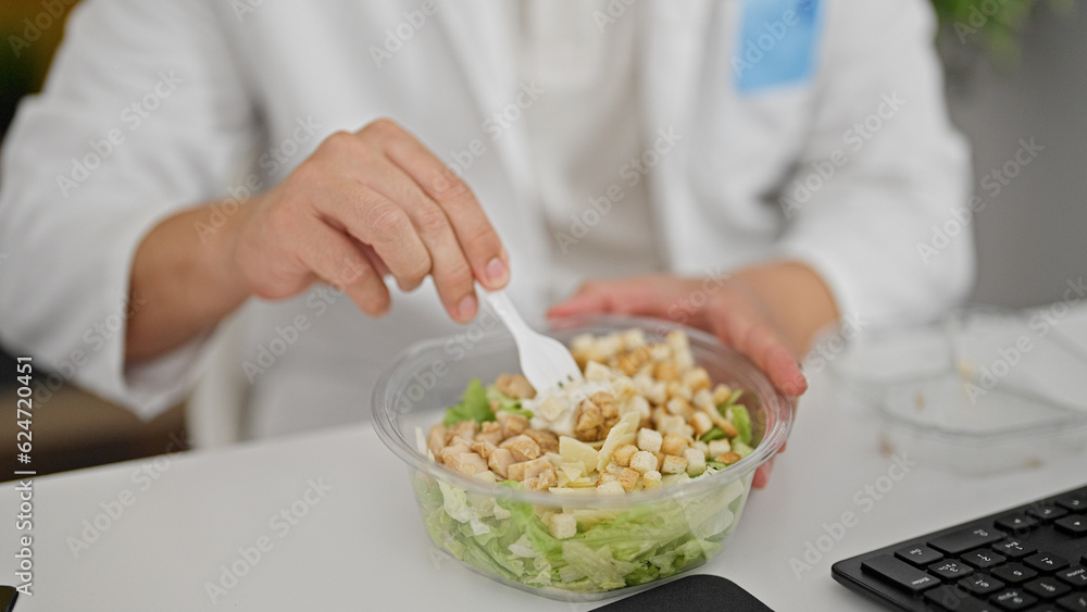 Grey-haired man doctor eating salad at the clinic