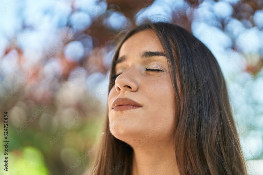 Young beautiful hispanic woman breathing with closed eyes at park Young beautiful hispanic woman breathing with closed eyes at park