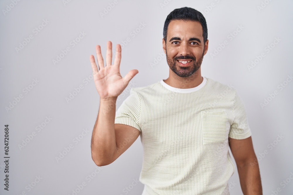 Hispanic man with beard standing over isolated background showing and pointing up with fingers number five while smiling confident and happy. Hispanic man with beard standing over isolated background showing and pointing up with fingers number five while smiling confident and happy.