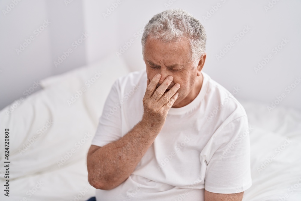 Middle age grey-haired man sitting on bed yawning at bedroom Middle age grey-haired man sitting on bed yawning at bedroom