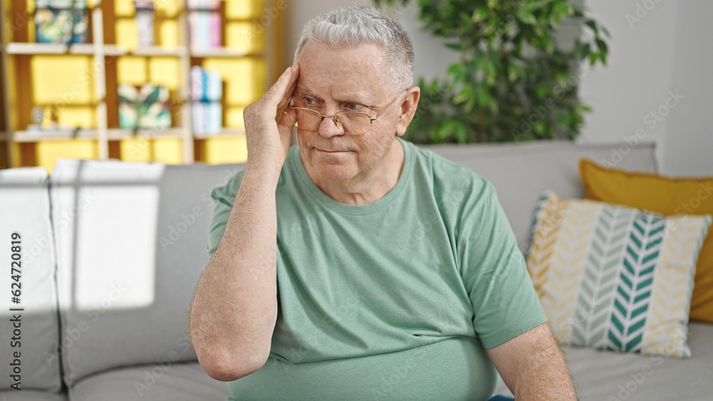 Middle age grey-haired man suffering for headache sitting on sofa at home Middle age grey-haired man suffering for headache sitting on sofa at home