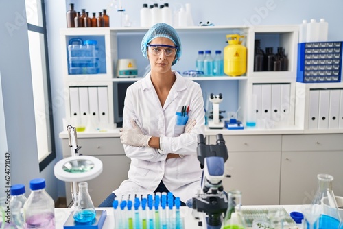 Brunette woman working at scientist laboratory skeptic and nervous  disapproving expression on face with crossed arms. negative person.