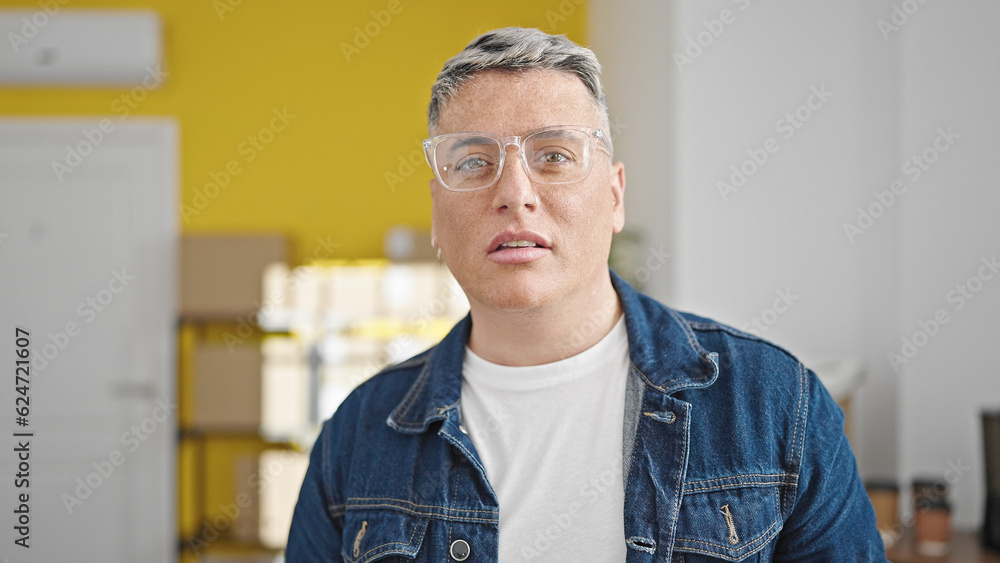Young caucasian man ecommerce business worker standing with serious face at office Young caucasian man ecommerce business worker standing with serious face at office