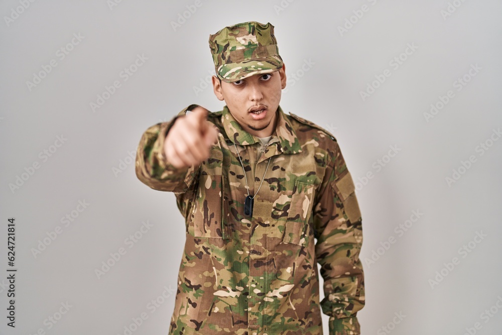 Young arab man wearing camouflage army uniform pointing displeased and frustrated to the camera, angry and furious with you Young arab man wearing camouflage army uniform pointing displeased and frustrated to the camera, angry and furious with you