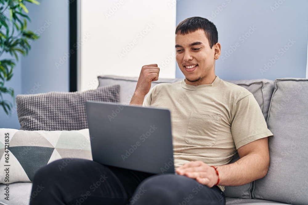 Young arab man using laptop at home pointing thumb up to the side smiling happy with open mouth Young arab man using laptop at home pointing thumb up to the side smiling happy with open mouth