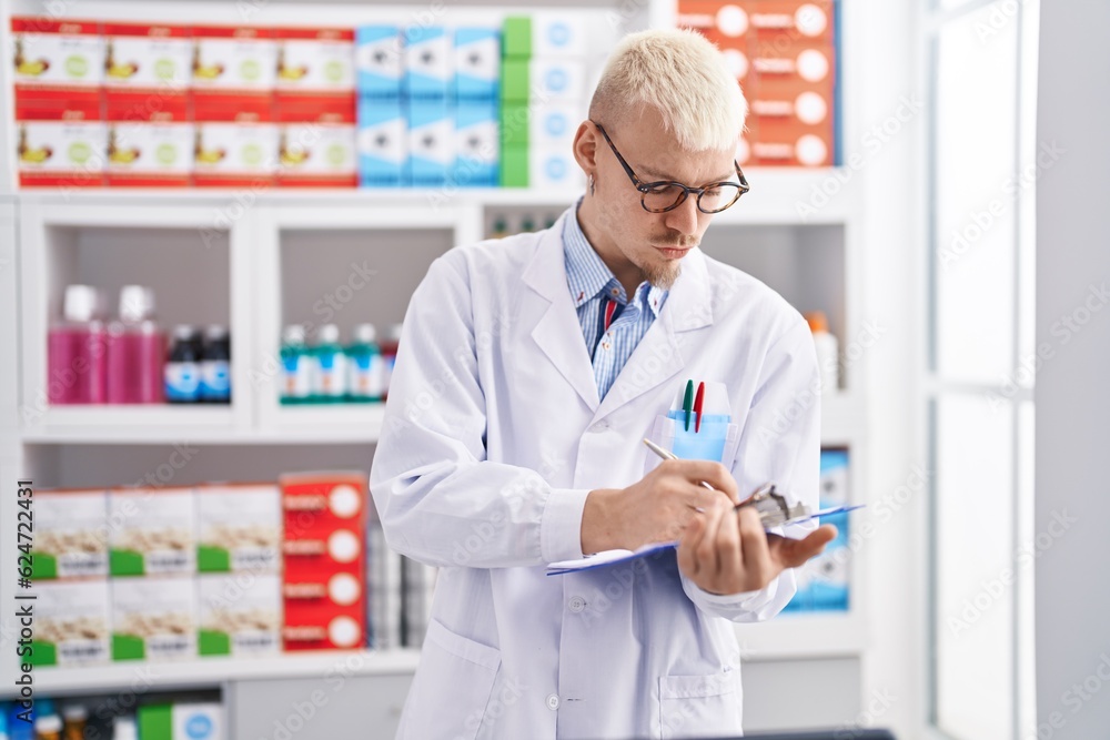 Young caucasian man pharmacist writing on document at pharmacy