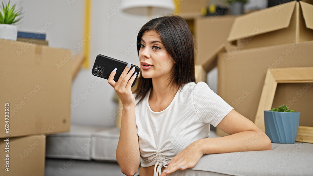 Young caucasian woman sending voice message by smartphone sitting on floor at new home Young caucasian woman sending voice message by smartphone sitting on floor at new home