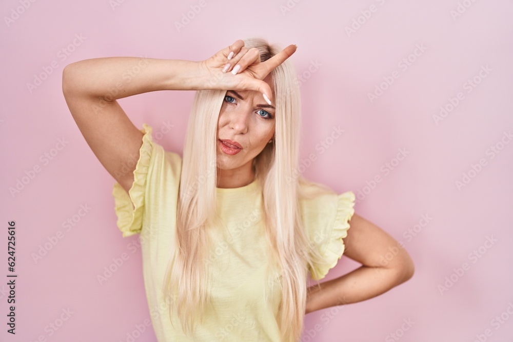 Caucasian woman standing over pink background making fun of people with fingers on forehead doing loser gesture mocking and insulting. Caucasian woman standing over pink background making fun of people with fingers on forehead doing loser gesture mocking and insulting.