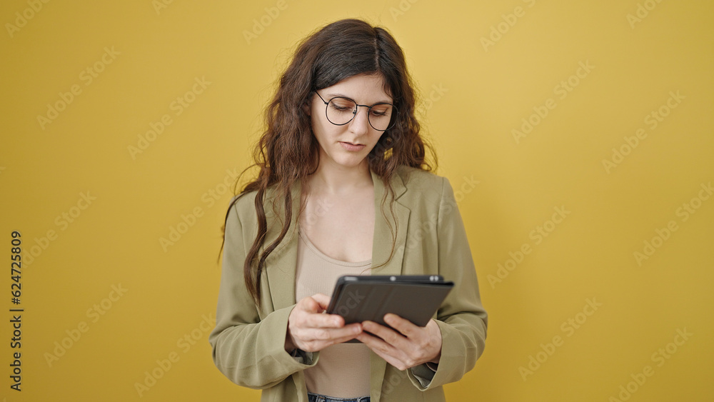Young beautiful hispanic woman smiling confident using touchpad over isolated yellow background Young beautiful hispanic woman smiling confident using touchpad over isolated yellow background