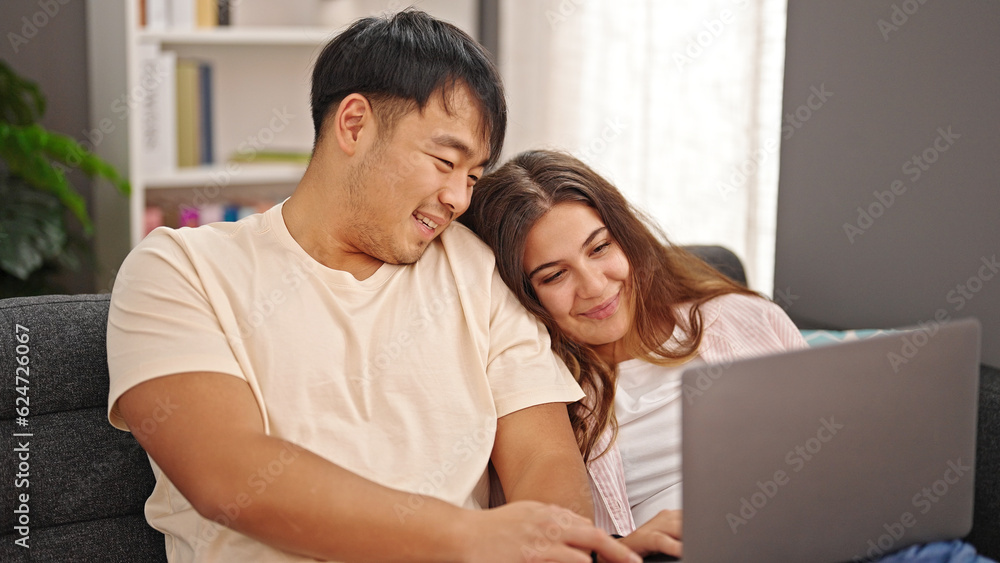 Man and woman couple sitting on sofa using laptop at home Man and woman couple sitting on sofa using laptop at home