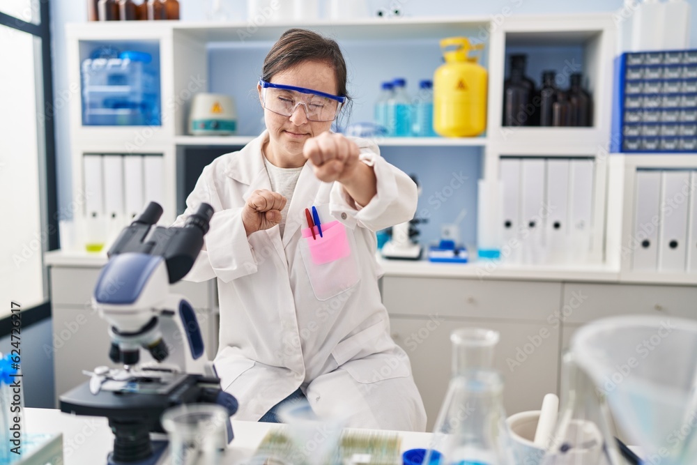 Hispanic girl with down syndrome working at scientist laboratory punching fist to fight, aggressive and angry attack, threat and violence