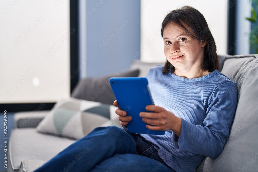 Young woman with down syndrome using touchpad sitting on sofa at home Young woman with down syndrome using touchpad sitting on sofa at home