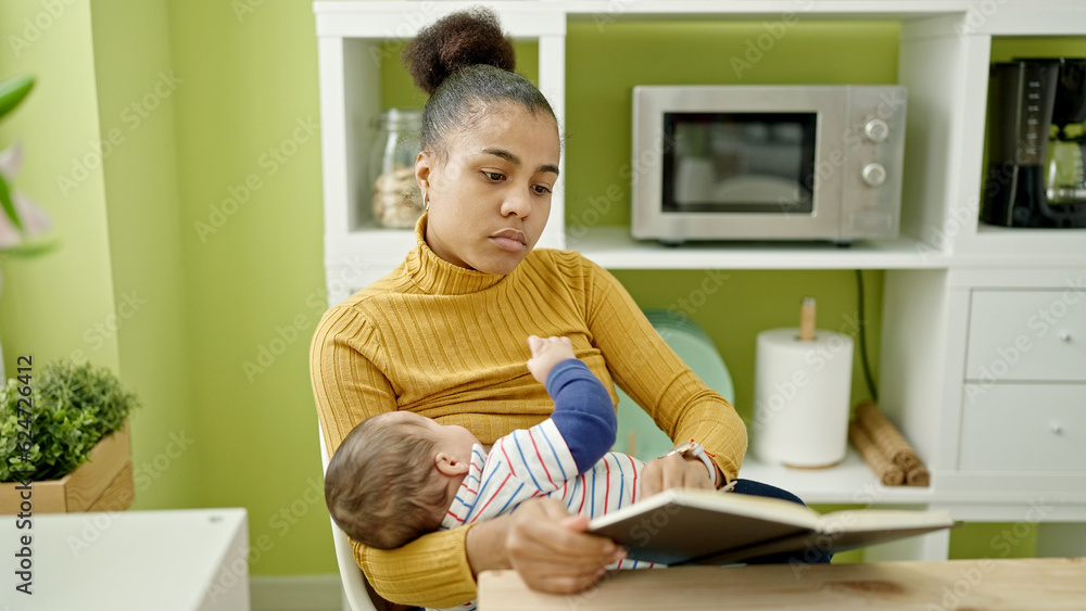 Mother and son reading book while breastfeeding baby at dinning room Mother and son reading book while breastfeeding baby at dinning room