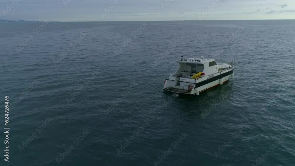 a fisherman with a yellow raincoat looking overboard. sport fishing, active lifestyle, hobbies and entertainment. Top view sailing fishing boat. deep sea fishing. a fisherman with a yellow raincoat looking overboard. sport fishing, active lifestyle, hobbies and entertainment. Top view sailing fishing boat. deep sea fishing.