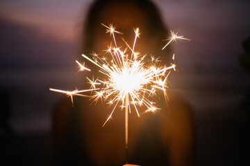 woman holding sparkles celebrating on tropical beach