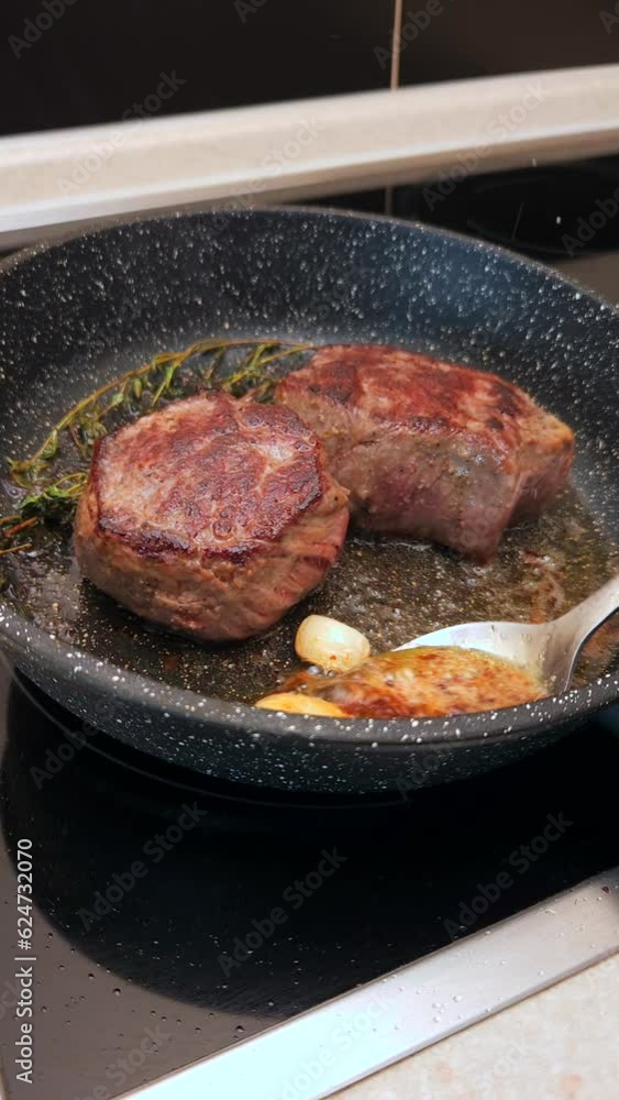 Pouring melted butter over filet mignon in a frying pan Pouring melted butter over filet mignon in a frying pan