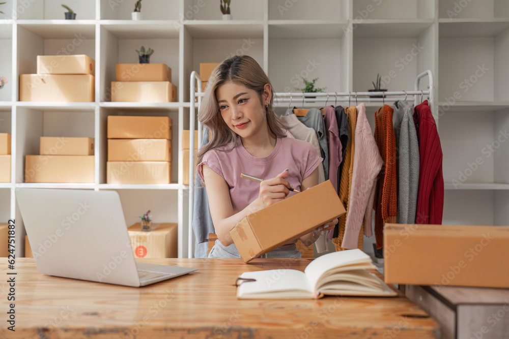 Woman designer stylish blogger entrepreneur is write the customer name in front of the box and taking receive online delivery order to prepare packing the product online shopping delivery Woman designer stylish blogger entrepreneur is write the customer name in front of the box and taking receive online delivery order to prepare packing the product online shopping delivery