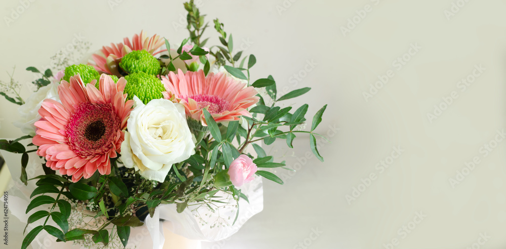 festive bouquet of white roses, pink gerberas and carnations in frame of green twigs on a light background. Birthday. Mother's Day. The concept of holiday flowers. Selective focus. Banner. Copy space